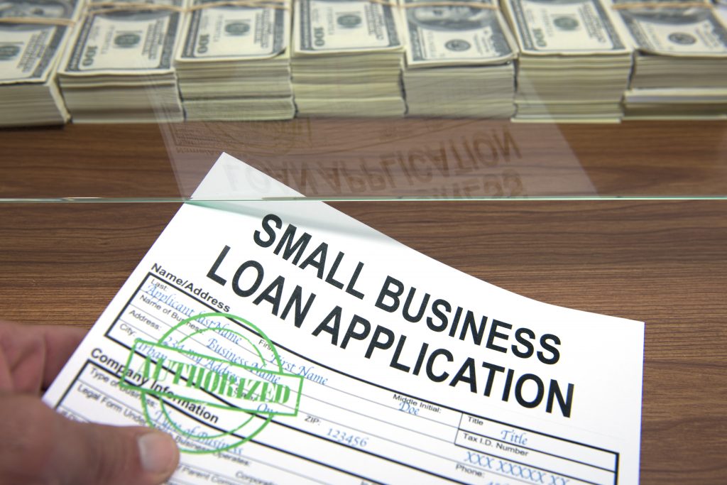 Approved small business loan application and dollar bills
