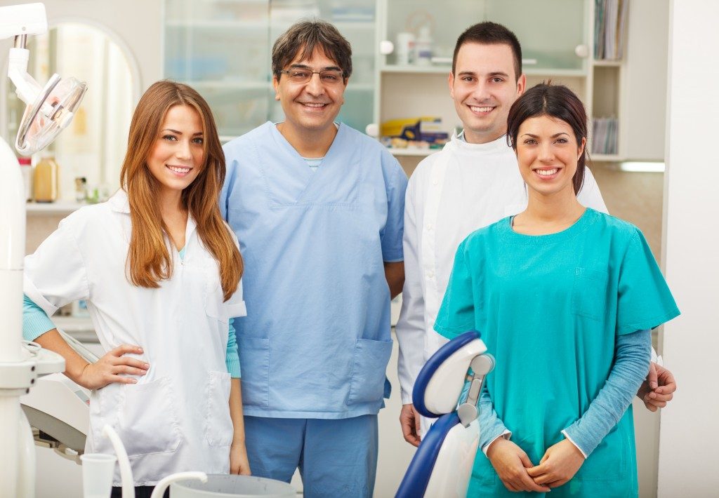 A dentist and his team posing together and smiling