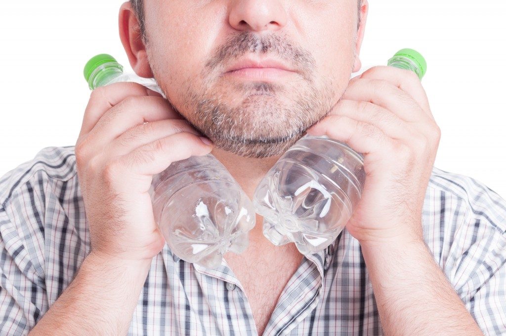 Man cooling his neck with cold bottled water