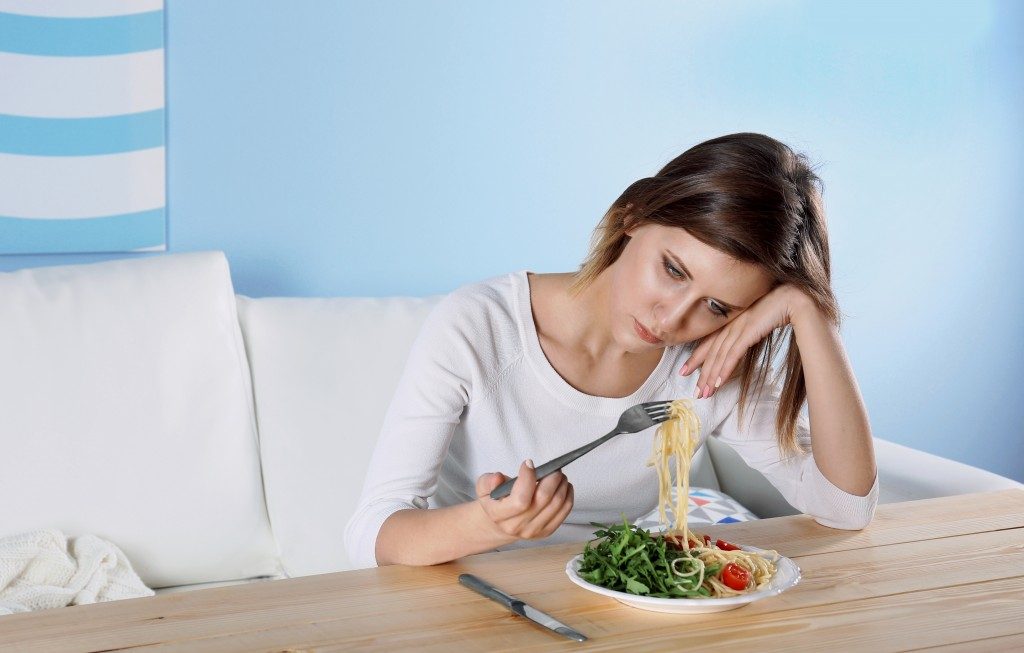 photo of a woman suffering from eating disorder, having a hard time eat her meal