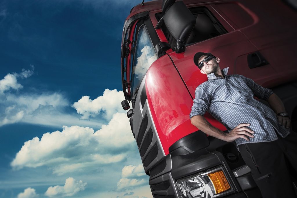 Truck driver posing beside a red truck