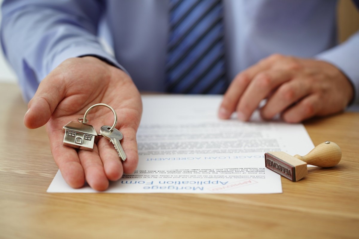 Person holding a key and mortgage application form