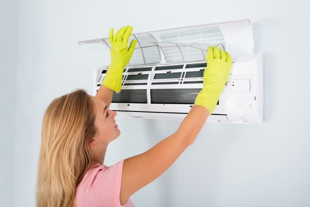 Woman Checking And Cleaning Air Conditioning System