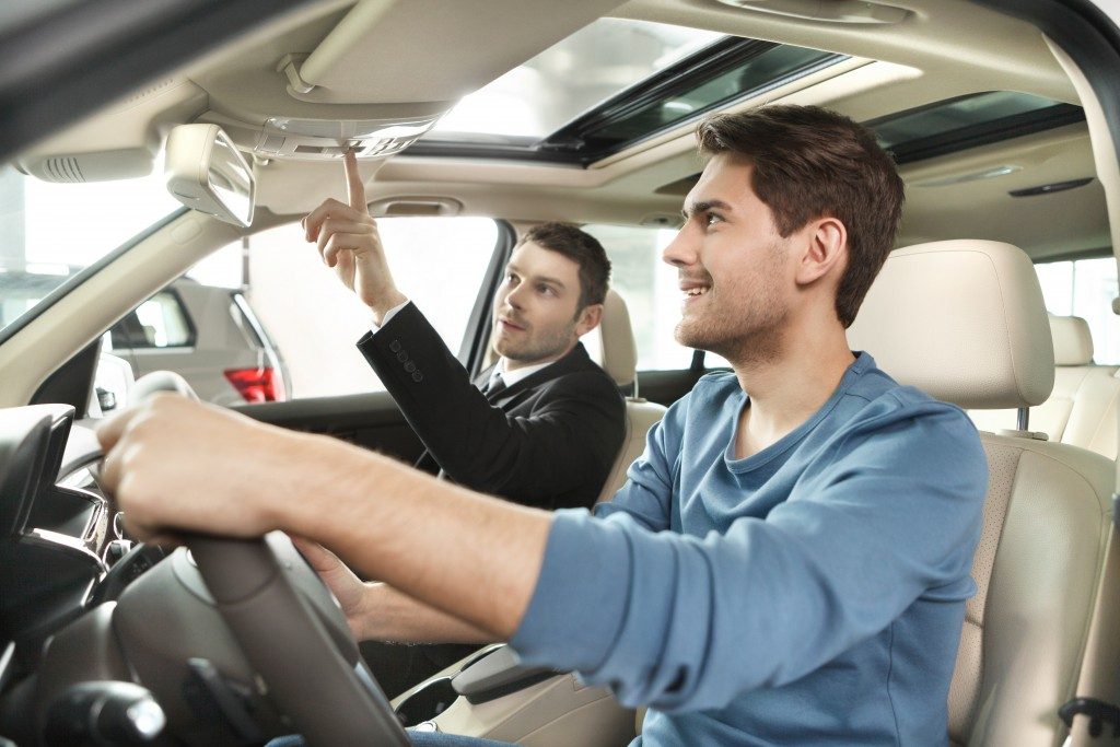 sales man showing potential buyer interior features of car