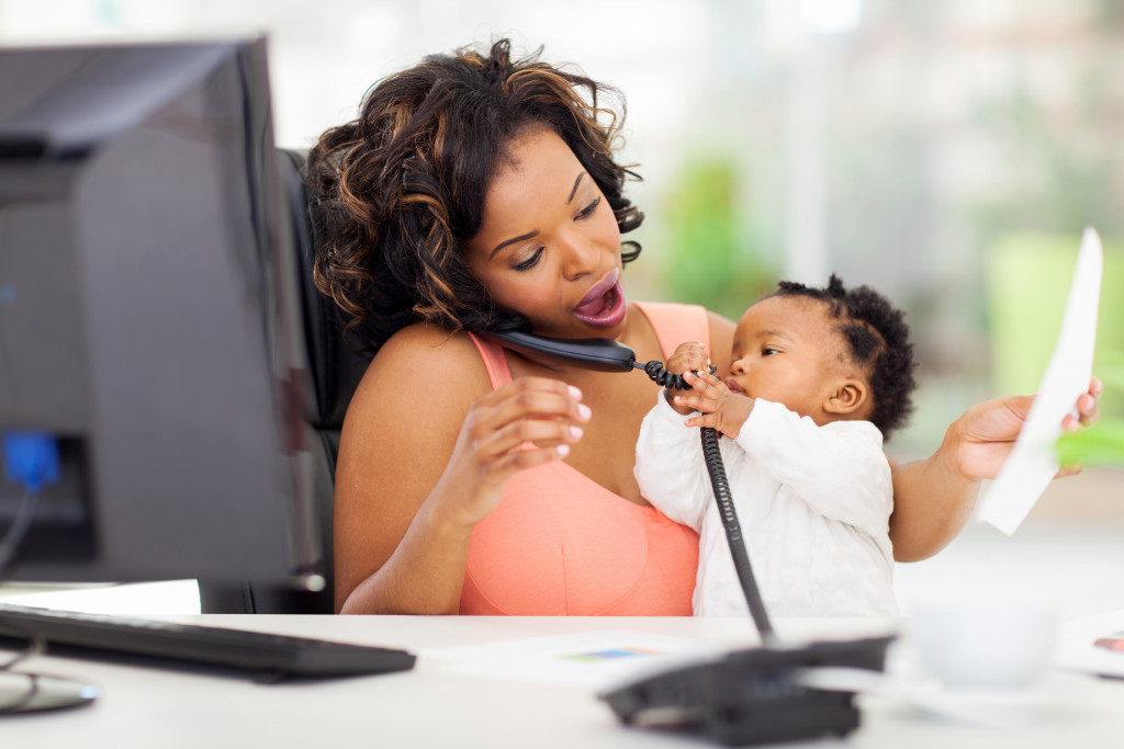 woman taking care of child while talking on the phone